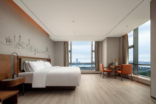 a hotel room with a bed and a table and chairs at UrCove by Hyatt Hangzhou Xiaoshan International Airport in Hangzhou