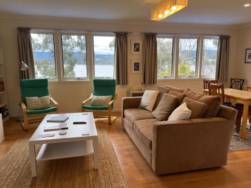 a living room with a couch and chairs and a table at Anchorage Waterfront Retreat in Castle Forbes Bay