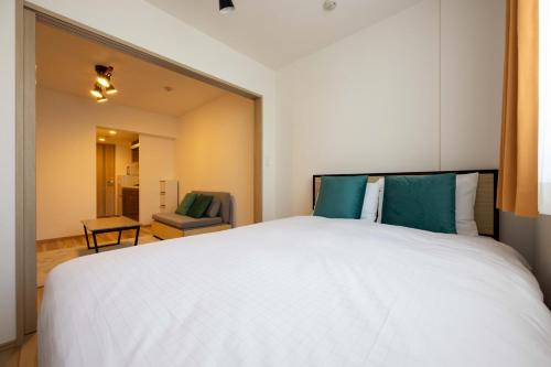 um quarto com uma grande cama branca e uma cadeira em Wellsquareism Otsuka em Tóquio