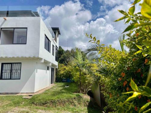 a white house with a yard with trees at BERAKHAH SPA & ROOMS in Guatapé