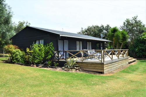 una casa nera con portico e cortile di Kai Iwi Lakes Resort a Kaihu