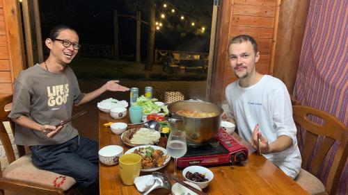 two men sitting at a table with a pot of food at Pea homestay in Sa Pa