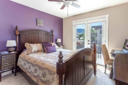 a bedroom with a bed with purple walls and a window at Peaches & Wine Villa Penticton in Penticton