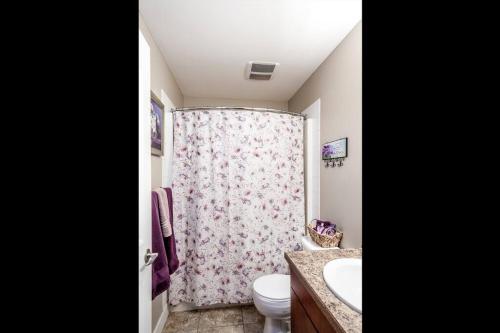 a bathroom with a toilet and a shower curtain at Peaches & Wine Villa Penticton in Penticton
