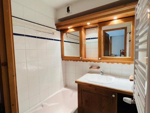 une salle de bain avec un lavabo, une baignoire et un miroir dans l'établissement Les Saisies : 3P, 2 SDB, Piscine, Parking, Animaux, 6 pers - FR-1-293-389, à Hauteluce