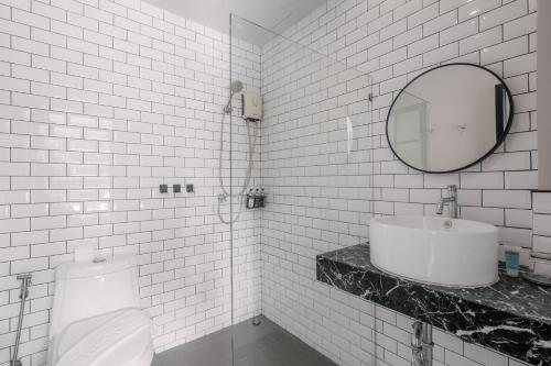 a white tiled bathroom with a sink and a toilet at Sugar Ohana Poshtel in Kata Beach
