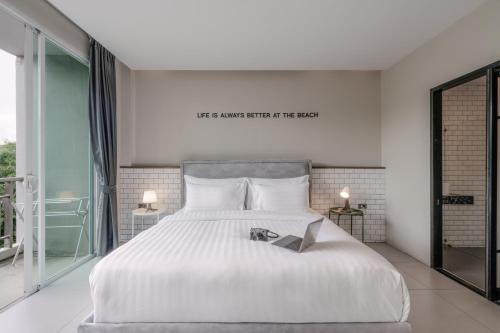 a bedroom with a white bed with a book on it at Sugar Ohana Poshtel in Kata Beach