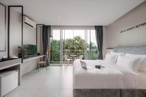 a bedroom with a large white bed and a television at Sugar Ohana Poshtel in Kata Beach