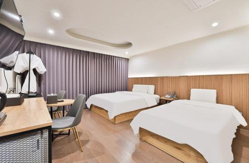 a hotel room with two beds and a desk at Beyond Hotel in Incheon