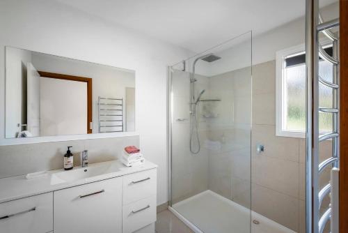 a white bathroom with a shower and a sink at Platypus Cottage Watch them play from the garden in Hobart