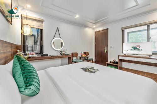 ein Schlafzimmer mit einem großen weißen Bett und einem grünen Kissen in der Unterkunft Charm Hill Sapa Hotel in Sa Pa