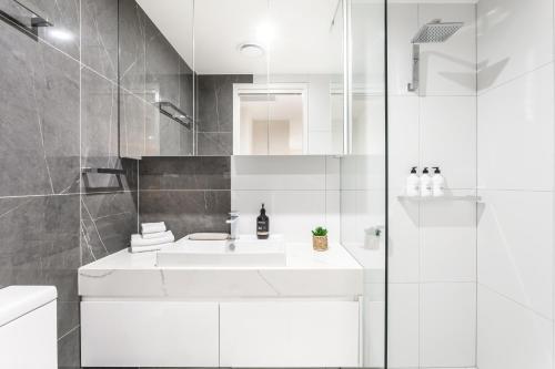 a white bathroom with a sink and a shower at Founders Lane Apartments by Urban Rest in Canberra