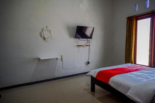 ein Schlafzimmer mit einem Bett und einem TV an der Wand in der Unterkunft OYO 93186 HKP Homestay in Blitar