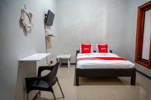 Schlafzimmer mit einem Bett mit roten Kissen und einem Schreibtisch in der Unterkunft OYO 93186 HKP Homestay in Blitar