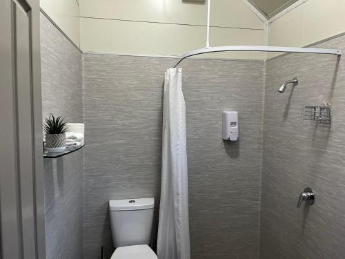 een badkamer met een douche, een toilet en een douchegordijn bij Hampshire Holiday Parks - Arrowtown in Arrowtown