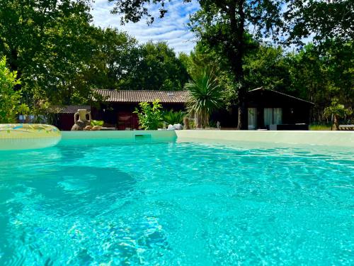 a large blue swimming pool in front of a house at Hacienda de la Canopée avec piscine chauffée au sel in Hourtin