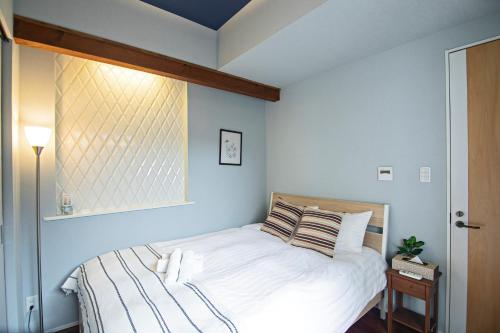 a bedroom with a white bed with a window at -粉浜飛鳥- 和風ヴィラ 玉出駅 in Osaka