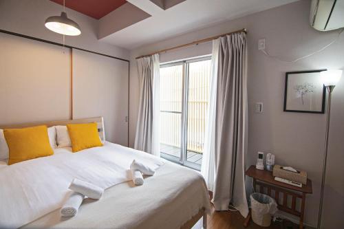 a bedroom with a bed with yellow pillows and a window at -粉浜飛鳥- 和風ヴィラ 玉出駅 in Osaka