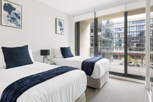 a bedroom with two beds and a large window at Founders Lane Apartments by Urban Rest in Canberra
