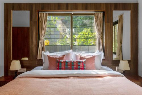 a bedroom with a large bed with pillows and a window at StayVista's Areca Villa - Mountain-View Haven with Private Pool & Indoor Fun in Nashik