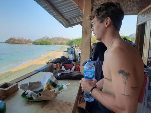 a man sitting at a table with a bottle of water at Boneputeh Homestay in Taliwang