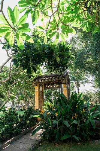 a sign in a park with trees and plants at Palm Garden Beach Resort & Spa in Hoi An