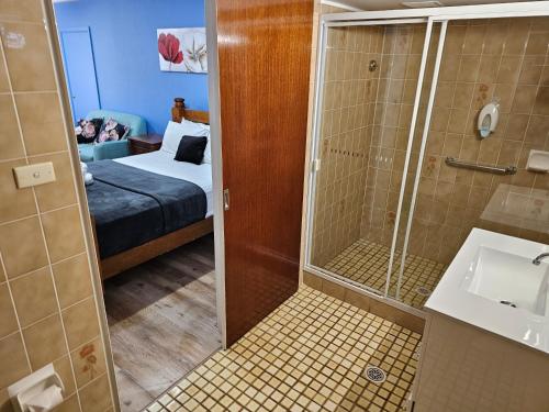 a bathroom with a shower and a bed and a sink at Cumberland Motor Inn in Cessnock