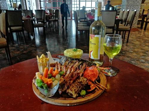 a plate of food with a bottle of wine and a glass at The Pharo in Nittambuwa