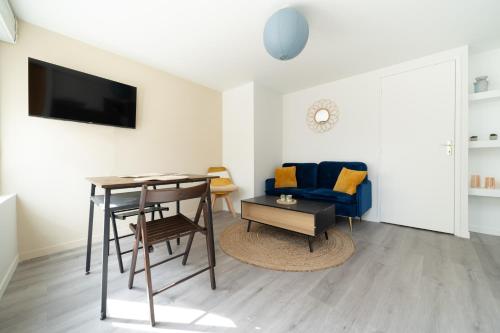 un salon avec une table et un canapé bleu dans l'établissement T2 idéal déplacement pro, entièrement rénové, à Rouen