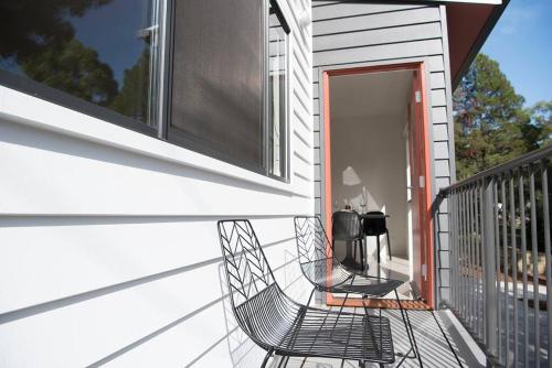 uma cadeira preta sentada no alpendre de uma casa em "Palm Retreat" - Private, Spacious and Bright em Noosa Heads