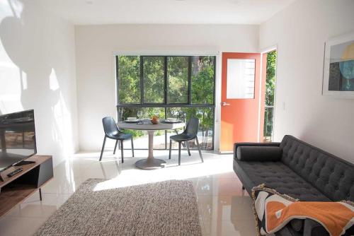 uma sala de estar com um sofá, uma mesa e cadeiras em "Palm Retreat" - Private, Spacious and Bright em Noosa Heads