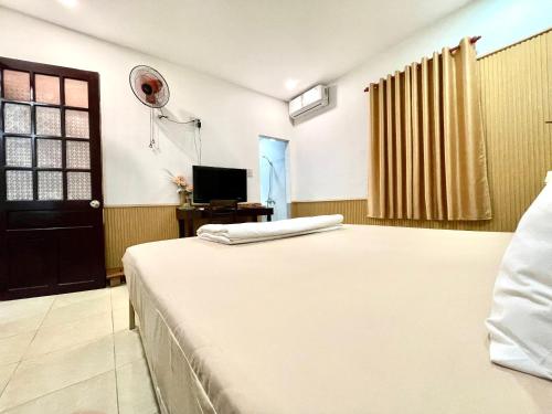 a bedroom with a bed and a tv and a door at Homestay MINH TÚ in Hue