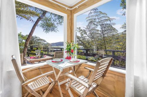 a dining room with a table and chairs and a large window at The Treehouse - Raglan Holiday Studio in Raglan