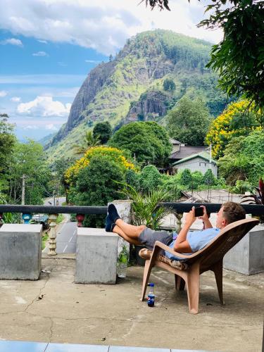 a man laying in a chair taking a picture of a mountain at Rock View Hostel Ella in Ella