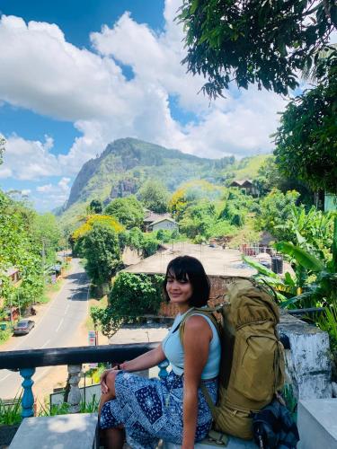 a woman sitting on a ledge with a backpack at Rock View Hostel Ella in Ella