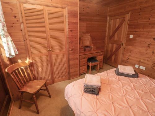 1 dormitorio con 1 cama y 1 silla en una cabaña en Acorn Lodge en Mydrim