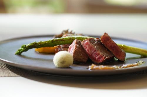 a plate of food with meat and asparagus at 北軽井沢　Golden Forest Hotel in Naganohara