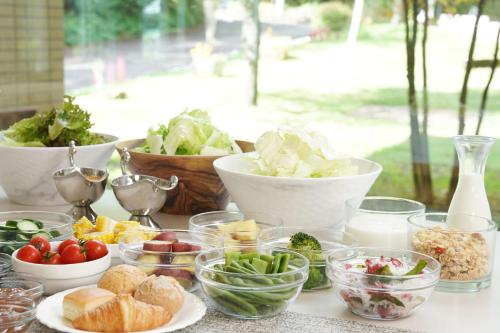 a table topped with bowls of vegetables and other foods at 北軽井沢　Golden Forest Hotel in Naganohara