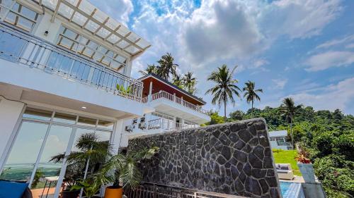 a large white building with palm trees in front of it at Caliraya Heights Resorts and Events Place in Halang