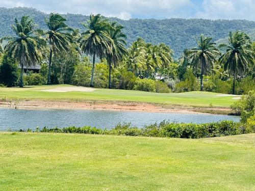 a golf course with palm trees and a pond at Paradise Escape - Poolside Ground Floor - Sea Temple Resort and Spa in Port Douglas