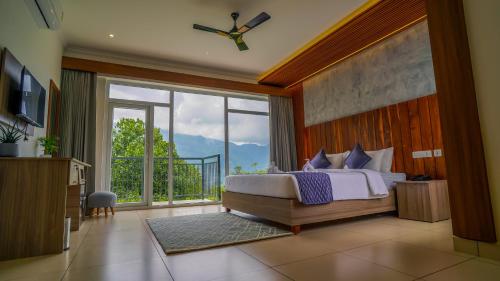 a bedroom with a bed and a large window at Winter Note Resorts in Munnar