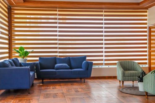 a living room with blue couches and a large window at Winter Note Resorts in Munnar
