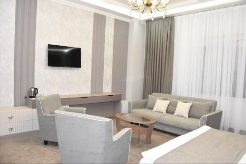 uma sala de estar com um sofá e uma televisão na parede em IMPERIAL em Taraz