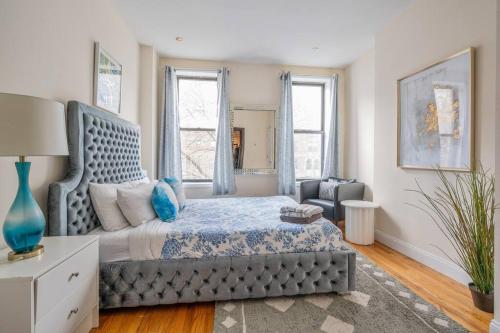 a bedroom with a bed and a chair and windows at Perfect Chic Apartment in Upper West of NYC! in New York