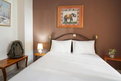 a bedroom with a bed with white sheets and a backpack at Litochoro apartment in Litochoro