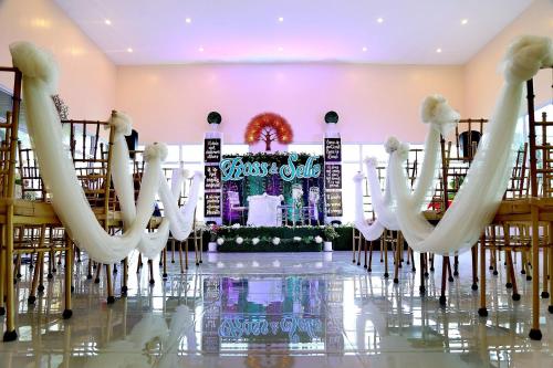 a wedding hall with white chairs and a stage at Mahalta Resorts and Convention Center in Calapan