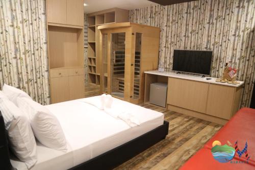 Mahalta Resorts and Convention Center في Calapan: غرفة نوم بسرير ابيض وتلفزيون