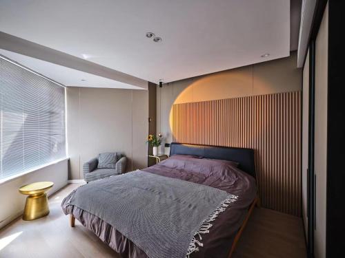 um quarto com uma cama, uma cadeira e uma janela em Datong Elite Apartment, Peoples Square, CBD em Xangai
