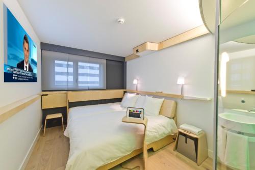 a small bedroom with a bed and a table at Nomad Hotel le Havre Centre Gare in Le Havre