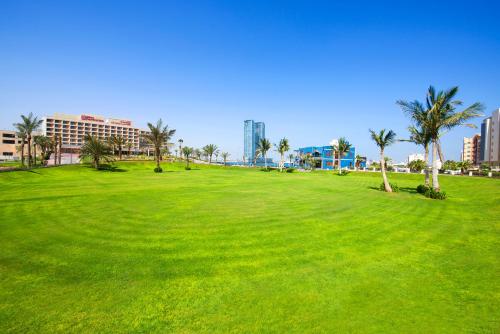 a green field with palm trees in a city at Hilton Garden Inn Ras Al Khaimah in Ras al Khaimah